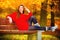 Portrait girl relaxing on bench in autumnal park.