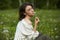 Portrait of a girl sitting in a field on the spring grass among dandelion flowers. Cheerful girl enjoys Sunny spring weather.