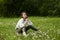 Portrait of a girl sitting in a field on the spring grass among dandelion flowers. Cheerful girl enjoys Sunny spring weather.