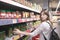 Portrait of a girl standing in a supermarket near a canned vegetable counter and looking into the camera