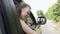 Portrait of the girl sticks her head out of the car window close up Wind flutters woman hair