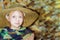 Portrait of a girl in a straw hat on the background of chopped wood and logs