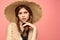 Portrait of a girl in a straw hat on a pink background emotions close-up beautiful face model pigtails