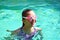 Portrait of a girl in swimming goggles. Happy girl swims in the pool