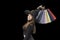 Portrait of girl in witchs hat with colorful paper shopping bags in hands. Black background. Copy space. Black Friday concept