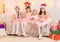 Portrait of girls celebrating christmas or new year, children dressed in santa helper hat, sitting on a couch in home interior