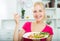 Portrait of glad young blond girl eating salad