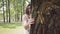 Portrait glamorous young girl with long brunette hair wearing a long white summer fashion dress standing next to a tree