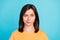 Portrait of gloomy funky serious cute girl with straight hairdo wear yellow t-shirt looks suspicious isolated on blue