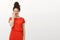 Portrait of good-looking flirty woman in cute red dress, covering half of face with palm and smiling broadly, checking