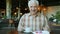 Portrait of good-looking senior man smiling sitting at table in restaurant