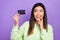 Portrait of good mood pretty girl wear stylish pullover interested look at credit card finger on lip isolated on violet