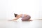 Portrait of gorgeous active sporty young woman practicing yoga in studio. Beautiful girl practice Ardha Kurmasana, half