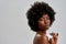 Portrait of gorgeous african american female model with afro hair touching her perfect glowing skin with white feather