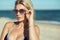 Portrait of a gorgeous blond lady in mirrored sunglasses and swimwear on the beach. Eyewear concept.