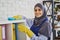 Portrait of a gorgeous Muslim woman cleaning shelves with books