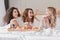 Portrait of gorgeous three women 20s wearing bathrobe having breakfast in bed in posh apartment or hotel room, during hen party i