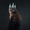 Portrait of a Gothic Princess. Beautiful young brunette woman in metal crown and black cloak.