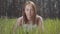 Portrait graceful cute young woman in the green grass around spectacular forest