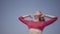 Portrait graceful woman in red long dress dancing raises hands on the big stone near spectacular view of blue sea water