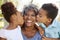 Portrait Of Grandchildren Kissing Grandmother In Park