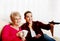 Portrait of granddaughter and grandmother sitting on couch and watching TV