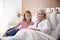 Portrait Of Granddaughter Visiting Grandmother In Hospital Bed