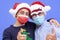 Portrait of a grandfather with teenager grandson smiling gesturing ok with hands, wearing mask due to coronavirus and santa hats.