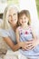 Portrait Of Grandmother And Granddaughter Sitting In Chair