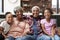 Portrait Of Grandparents Sitting On Sofa At Home With Granddaughters