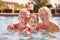 Portrait Of Grandparents Teaching Granddaughter To Swim On Family Summer Holiday In Pool 