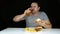 Portrait of a greedy fat man eating burger on black background
