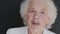 Portrait of grey-haired grandmother talks and smiles at camera on background