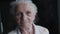 Portrait of grey-haired grandmother with wrinkled face talks easy into camera