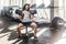 Portrait of grimace young adult muscular built athlete with long curly hair working out in gym, sitting on weightlifting machine,