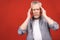 Portrait of a groggy upset worried sad, depressed, tired senior man with a headache, very stressed, isolated on red background,