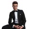 Portrait of groom wearing glasses and black tuxedo sitting