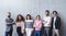 Portrait of group of entrepreneurs standing against concrete wall indoors in office, looking at camera.