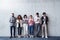 Portrait of group of entrepreneurs standing against concrete wall indoors in office, using smartphone.