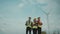 Portrait of a group of happy engineers looking in an agricultural field with wind turbines. Renewable and clean energy concept