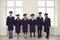 Portrait of a group of multiracial university graduates in academic dresses standing holding hands.