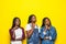Portrait of group of three beautiful african women with hand on chin thinking about question, pensive expression over yellow