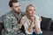 portrait grown son in military uniform hugging pensive mother on sofa