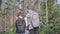 Portrait of guy and young girlfriend walking in the forest. Pair of travelers with backpacks outdoors. Leisure couples