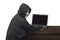 Portrait of hacker man with mask looking back while typing laptop on desk