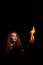 Portrait of a Halloween witch imposes a flame spell. Beautiful redhead woman doing witchcraft holds fire in her hands