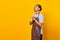 Portrait of handsome Asian young man wearing apron praying, believing in master on yellow background