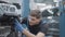 Portrait of handsome auto mechanic checking breakage of disassembled car in repair shop. Concentrated young Caucasian