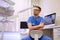 Portrait of a handsome bearded dentist male in glasses wearing a blue uniform, sitting in a dentist office.