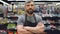 Portrait of handsome bearded guy experienced salesman in apron standing in toy department in supermarket, looking at